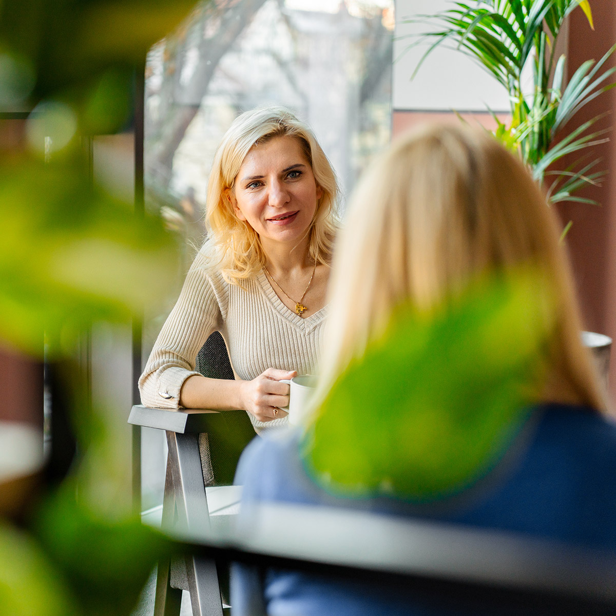 7N Team Member Sitting With Coffee Mug in front of the other colleague