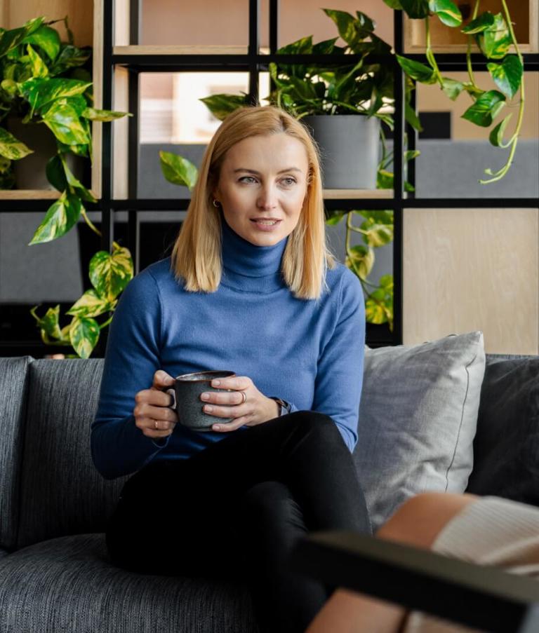 A woman sitting with a cup of coffee while talking to another woman in the Gdansk office in Poland. 