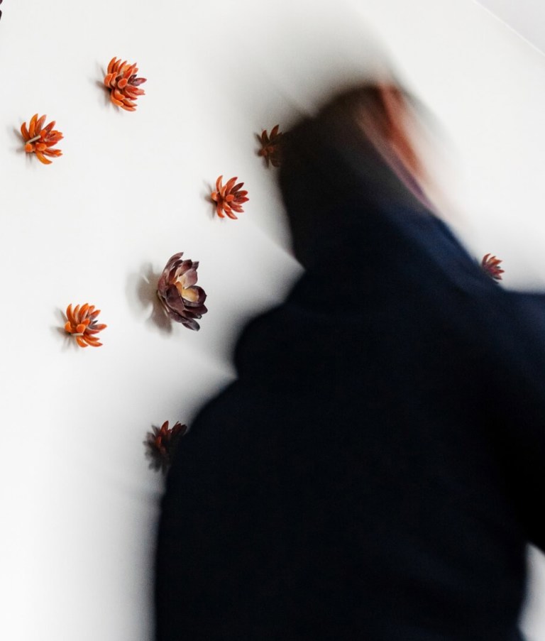 Man walking fast by a white wall with flowers in the Warsaw office in Poland. 