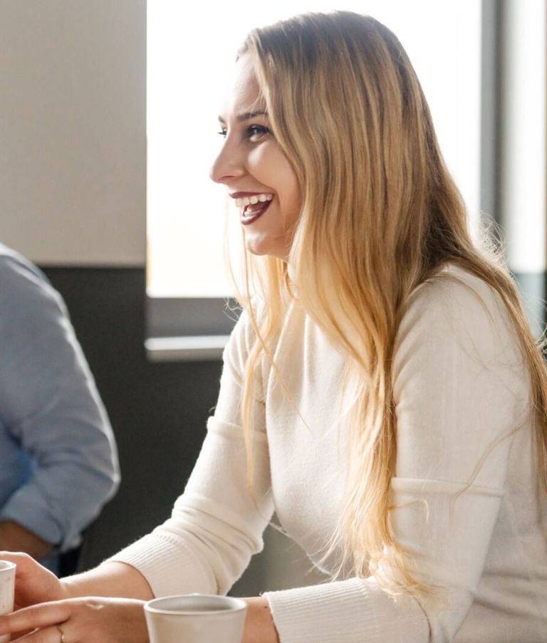 A man and a woman laughing at a table in the Warsaw office, Poland.